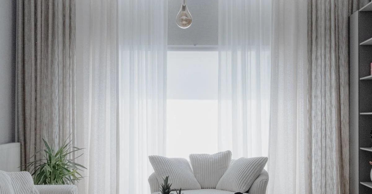 Un salon minimaliste avec des canapés blancs doux et de grands rideaux, créant une atmosphère chaleureuse.
